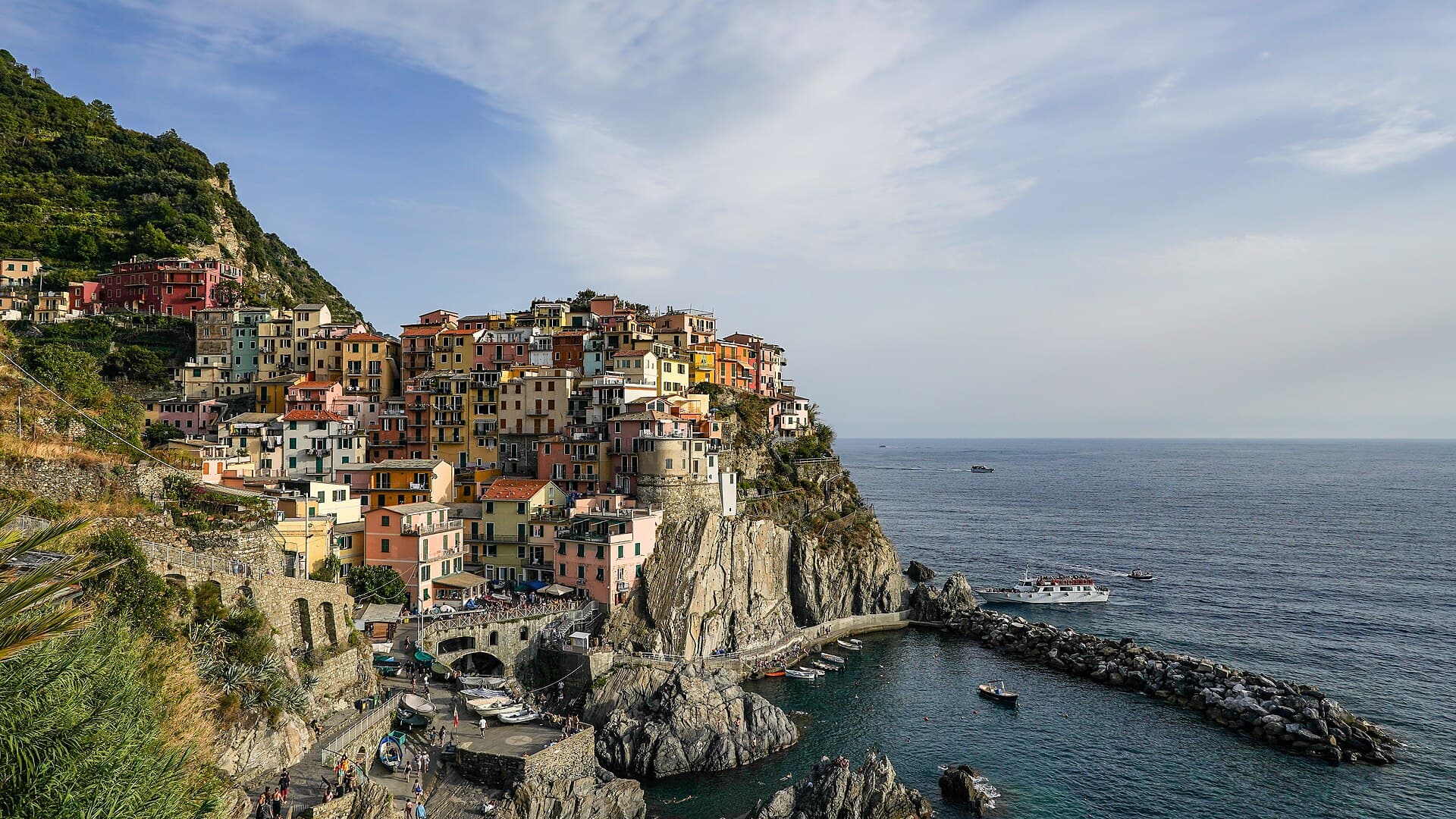 Manarola seen from the coastal path, its coloured houses stacked on a cliff above a small harbour