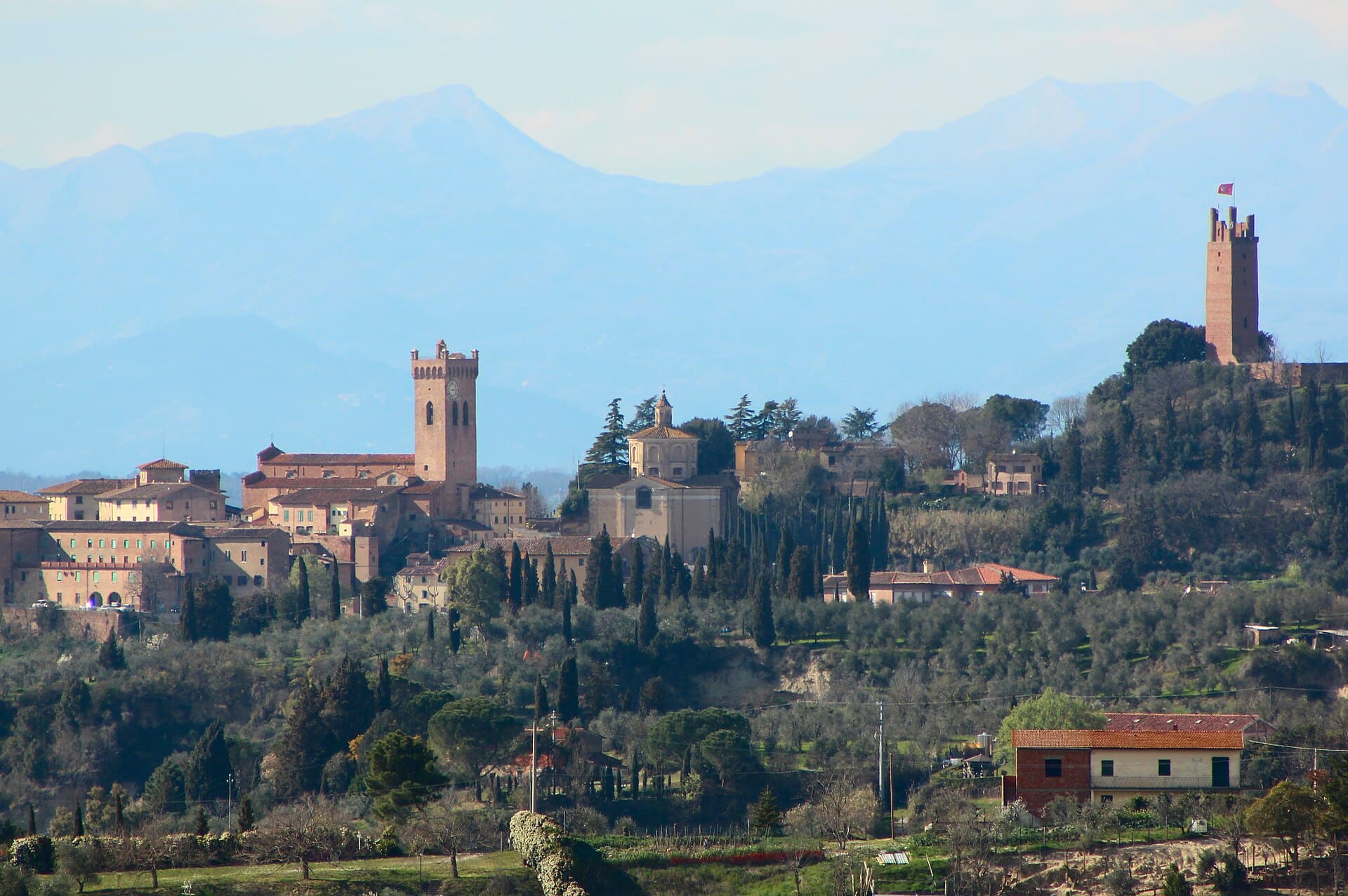 San Miniato on its ridge with the brick campanile of the cathedral in the centre and Frederick II's tower on the hill to the right, olive terraces below and hazy mountains behind